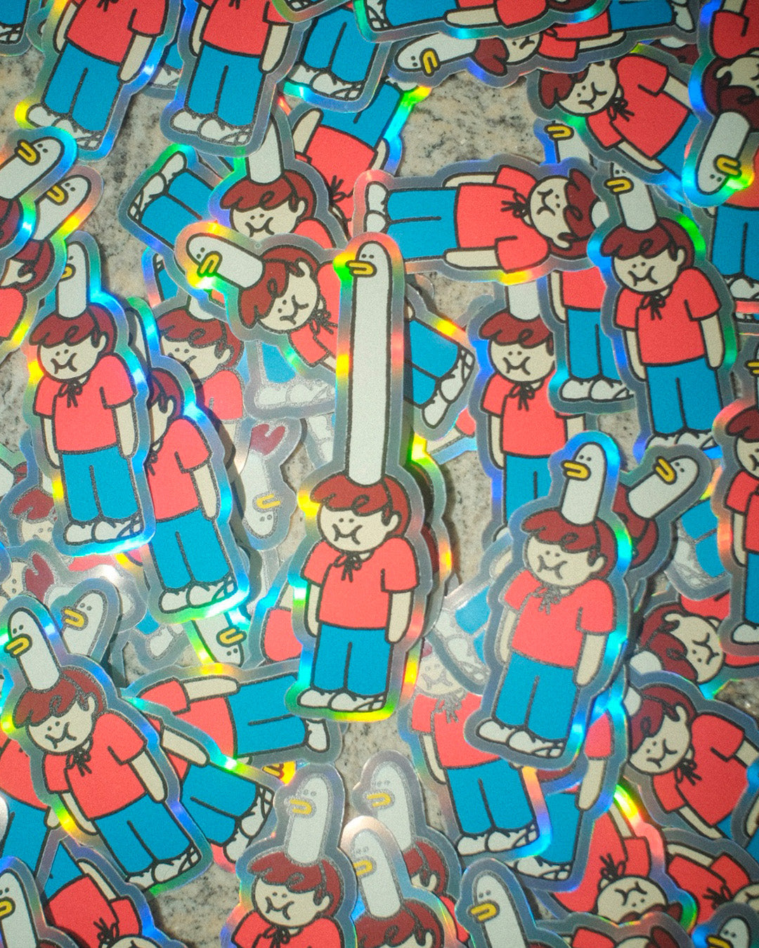 A holographic sticker of a character with red shirt and blue pants, wearing a comically long goose-shaped hat, on a textured surface. That sticker is surrounded by similar stickers, but with shorter goose hats.