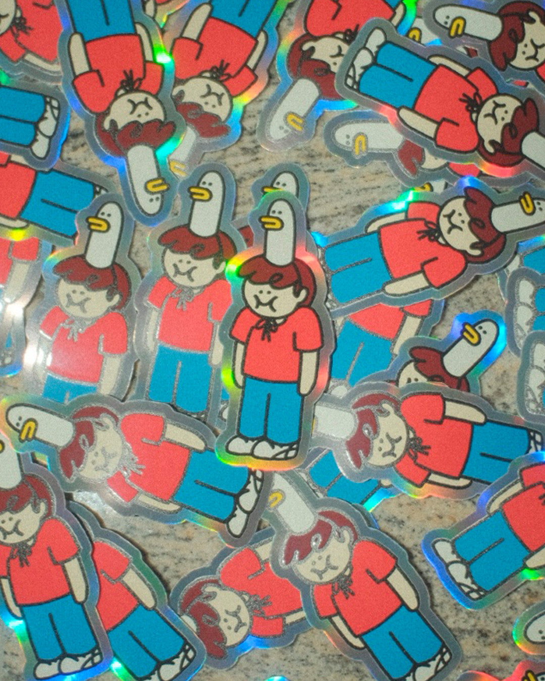 Holographic stickers of a character in red shirt and blue pants, wearing a goose-shaped hat, on a textured surface.